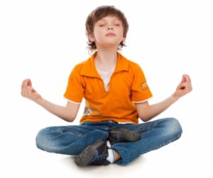 The little boy in a lotus pose meditates. Yoga
